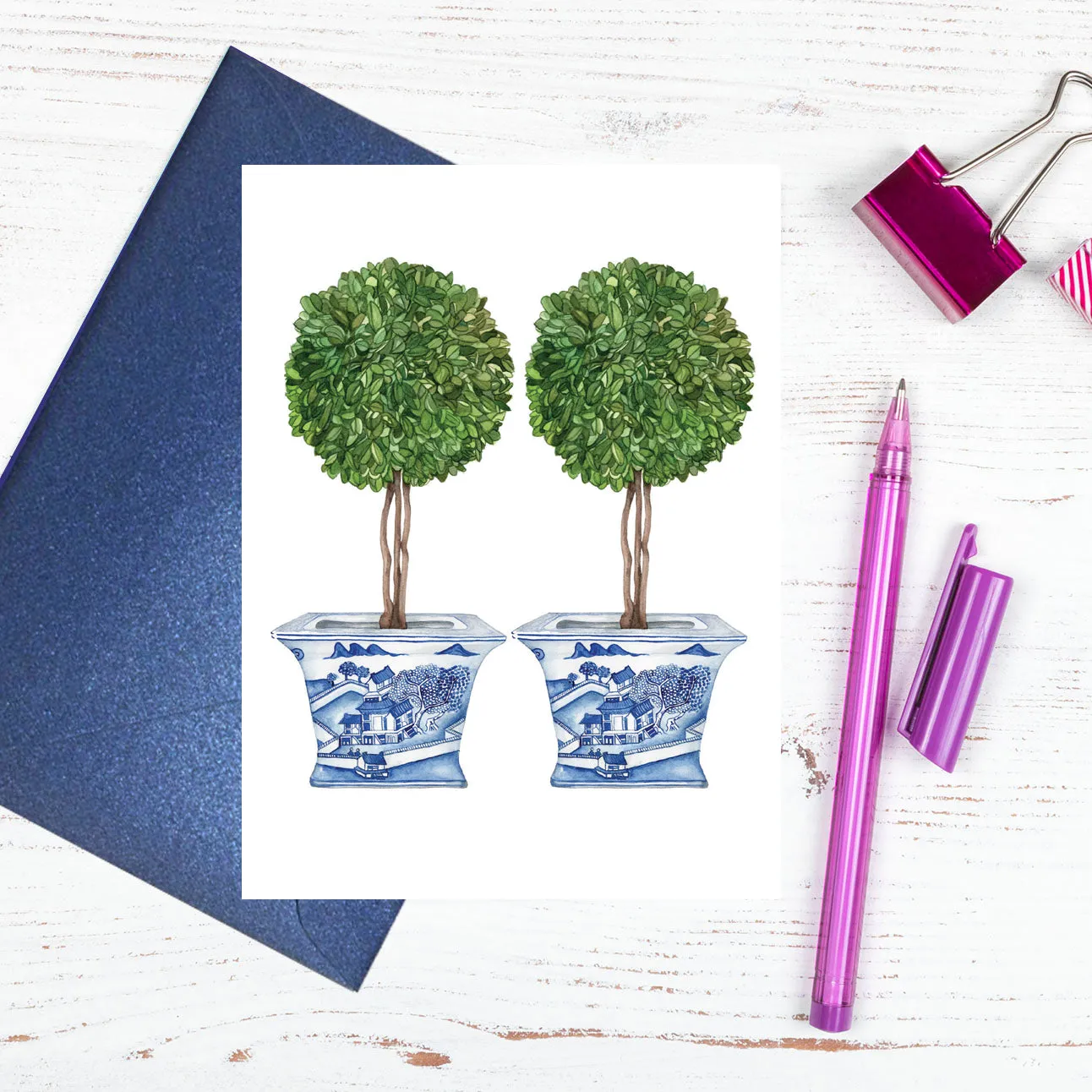 A blue and white card with topiary trees